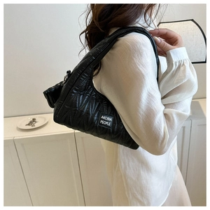 Detail of black quilted shoulder bag with brand label and stylish geometric stitching