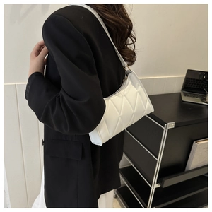 Side view of white quilted faux leather underarm bag with gold accents on a model