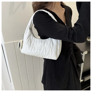 Close-up of white quilted tote bag with matching mini pendant pouch on black dress