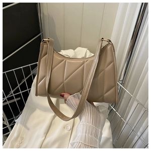 Close-up of beige quilted shoulder bag with diamond stitching texture and flat strap