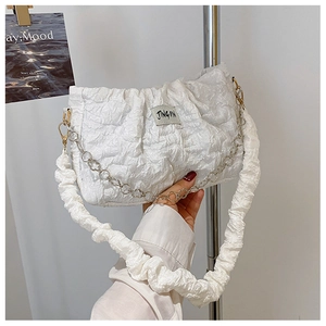Détail d'un sac à main blanc plissé avec tissu texturé et chaîne en métal à fleurs