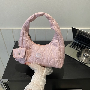 Pink quilted half-moon hobo bag with thick handle and mini coin purse in city office setting