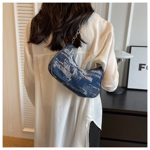 Close-up of denim hobo bag with silver chain strap shown in a minimalist home setting