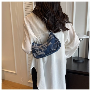 Detail of blue denim hobo bag with silver chain strap shown on model's shoulder