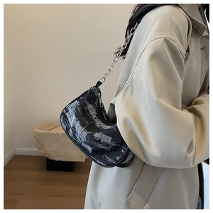 Detail of black denim hobo bag featuring frayed edges and silver metal chain strap