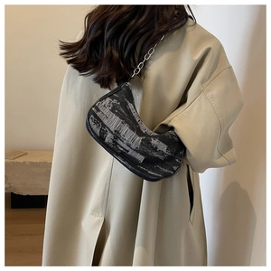 Detail showing vintage denim shoulder bag with metal chain on beige coat model shoulder