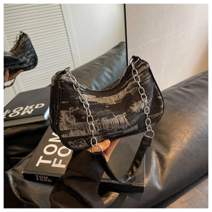 Close-up of distressed black denim shoulder bag with silver chain and leather strap