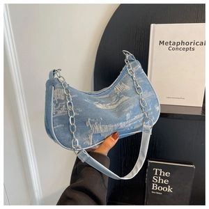 Detailed view of denim shoulder bag with silver chain strap and distressed frayed edges