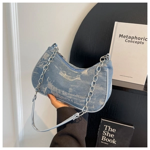 Close-up of distressed blue denim shoulder bag with silver metal chain strap and frayed edges
