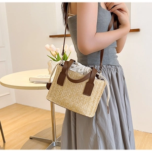 Vista dettagliata di una borsa a secchiello in paglia intrecciata con finiture in pelle marrone