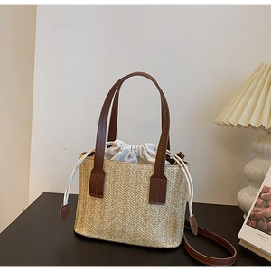 Dettaglio borsa in paglia intrecciata con texture a V e chiusura a coulisse in tessuto