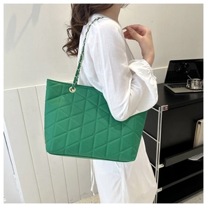 Detail of vibrant green quilted tote bag featuring gold-tone chain strap and triangle stitching