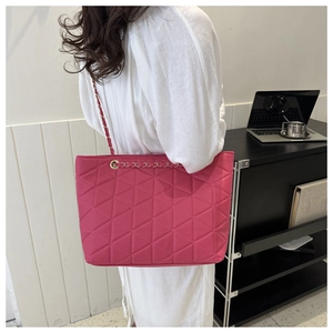 Detail of rose pink quilted tote bag with chain strap worn with a white knit dress