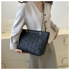 Detail of geometric quilted matte black tote bag with chain strap and metallic eyelets