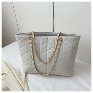 Detail of quilted diamond pattern and gold chain leather strap on the beige tote bag