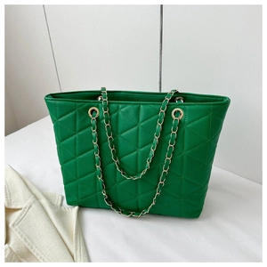 Detail of green quilted tote bag with golden metal chain strap on minimalist background