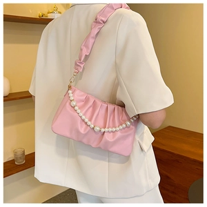 Sac à bandoulière froncé rose avec chaîne de perles porté sur un blazer blanc chic