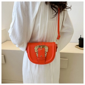 Close-up of bright orange saddle bag featuring a gold baroque-style buckle detail