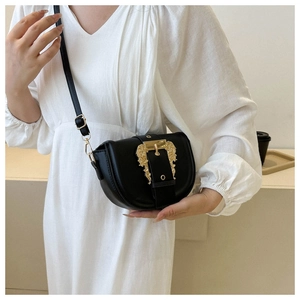 Close-up of black leather bag featuring ornate gold Baroque style embossed metal buckle