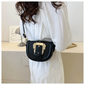 Close-up of black saddle bag featuring a large golden baroque engraved buckle and strap