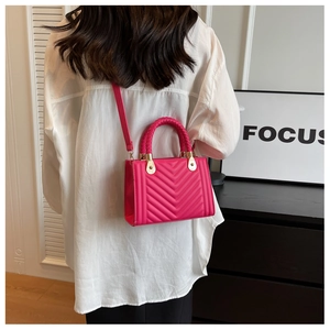 Detail of fuchsia mini crossbody bag with V-quilted pattern and braided handle