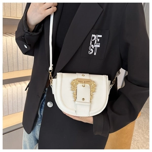 Detail of white saddle bag with ornate gold baroque buckle and fine floral embossing