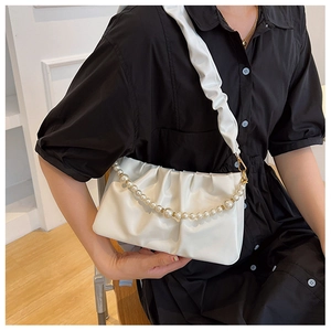 Sac à bandoulière blanc plissé avec chaîne en perles porté par un mannequin en studio