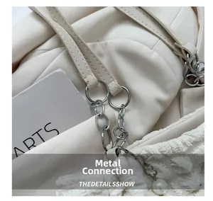 Close-up of bubble textured white tote with silver metal rings and pearl flower charm