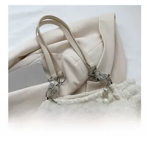 Close-up of cream puffy tote bag with decorative pearl, flower charm and metal chain detail