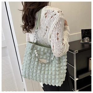 Detail of light green tote bag featuring bubble texture fabric and pearl chain handle