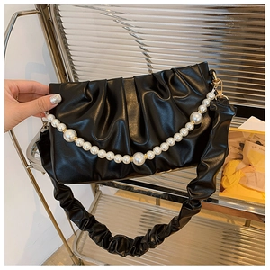 Détail d'un sac à fronces noir avec grande chaîne en perles et boucles métalliques dorées