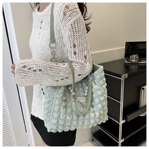 Detail of light green ruched tote bag featuring pearl chain strap and 3D textured fabric