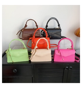 Close-up of pleated textured mini handbags in diverse colors with knotted handle detail