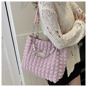 Detail of pink bubble texture tote bag featuring pearl chain and leather logo patch