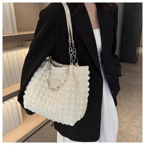 Detail of creamy white pleated tote bag with silver chain and elegant pearl decoration