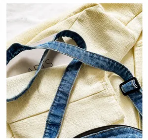 Close-up of blue denim shoulder bag strap featuring an adjustable black plastic buckle