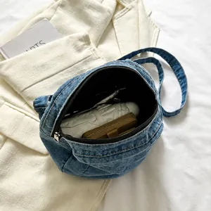 Interior capacity of denim shoulder bag showing a wallet and soft inner lining