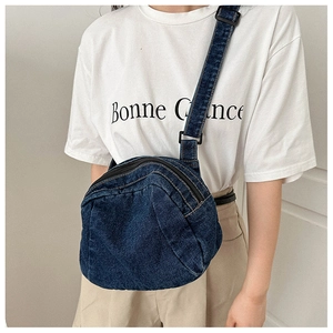 Detail of blue denim crescent crossbody bag with zipper closure and adjustable strap