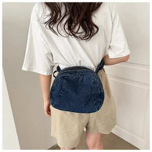 Detail of navy blue denim crescent bag shown on model with washed denim texture
