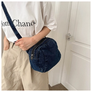 Model wearing dark blue denim crescent crossbody bag with zipper detail and strap