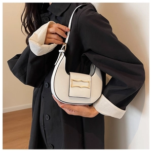 Gros plan sur un sac hobo demi-lune en cuir blanc avec une boucle en métal doré