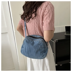 Detail of blue denim crescent crossbody bag showing the fabric texture and strap