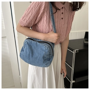 Detail of classic blue denim crossbody bag with double zipper and washed texture