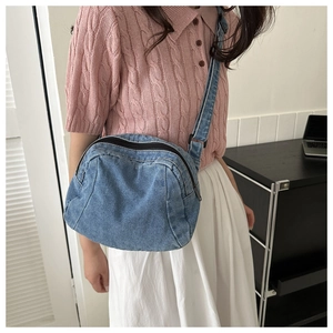 Detail of trendy washed blue denim crossbody bag with adjustable wide strap on model