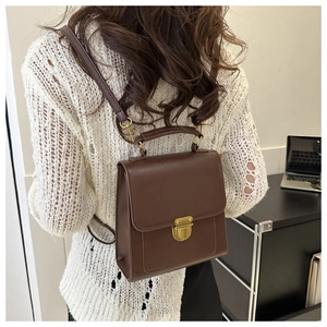 Vista posteriore di uno zaino vintage in pelle marrone su modella con top bianco
