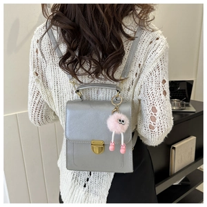 Zaino in pelle PU argento con chiusura dorata e ciondolo di peluche rosa su modello