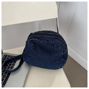 Detail of a dark blue denim crossbody bag with vintage washed finish on a chair