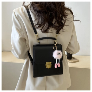 Zaino in pelle nera opaca con fibbia dorata e ciondolo di peluche indossato dalla modella