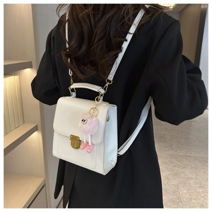 Dettaglio zaino in pelle bianca con fibbia dorata e ciondolo di peluche rosa