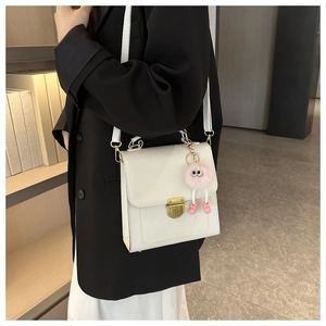 Borsa a tracolla bianca con fibbia dorata e un simpatico ciondolo a forma di mostro rosa
